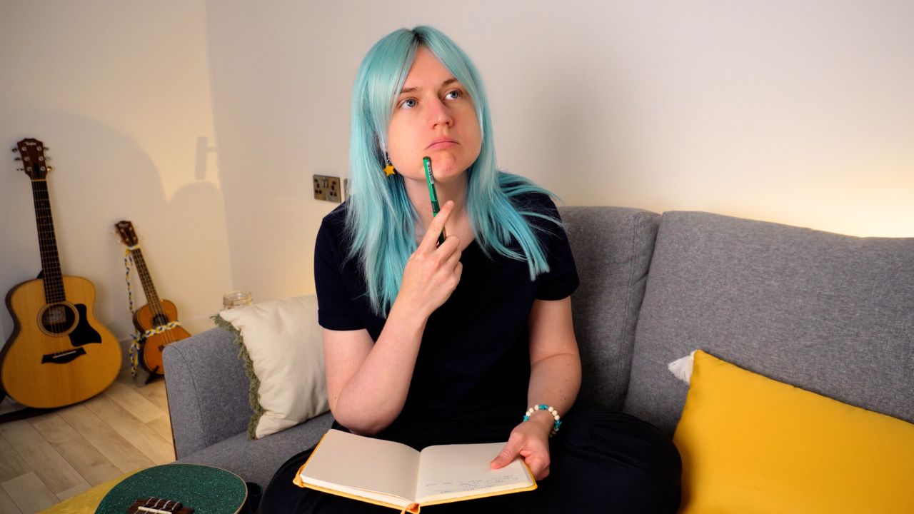 emily fable thinking on sofa with notebook